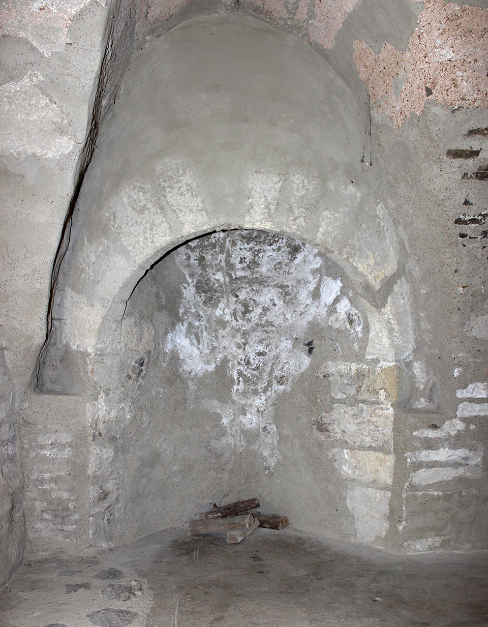 Romanesque fireplace in the wine cellar with a protruding chimney and carefully carved arched stones, circular vent, c. 1200